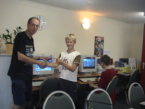 Bert Loos reikt een gratis kaart uit aan Pascal Verbiest, terwijl aan de computer GTA 3 wordt gespeeld.